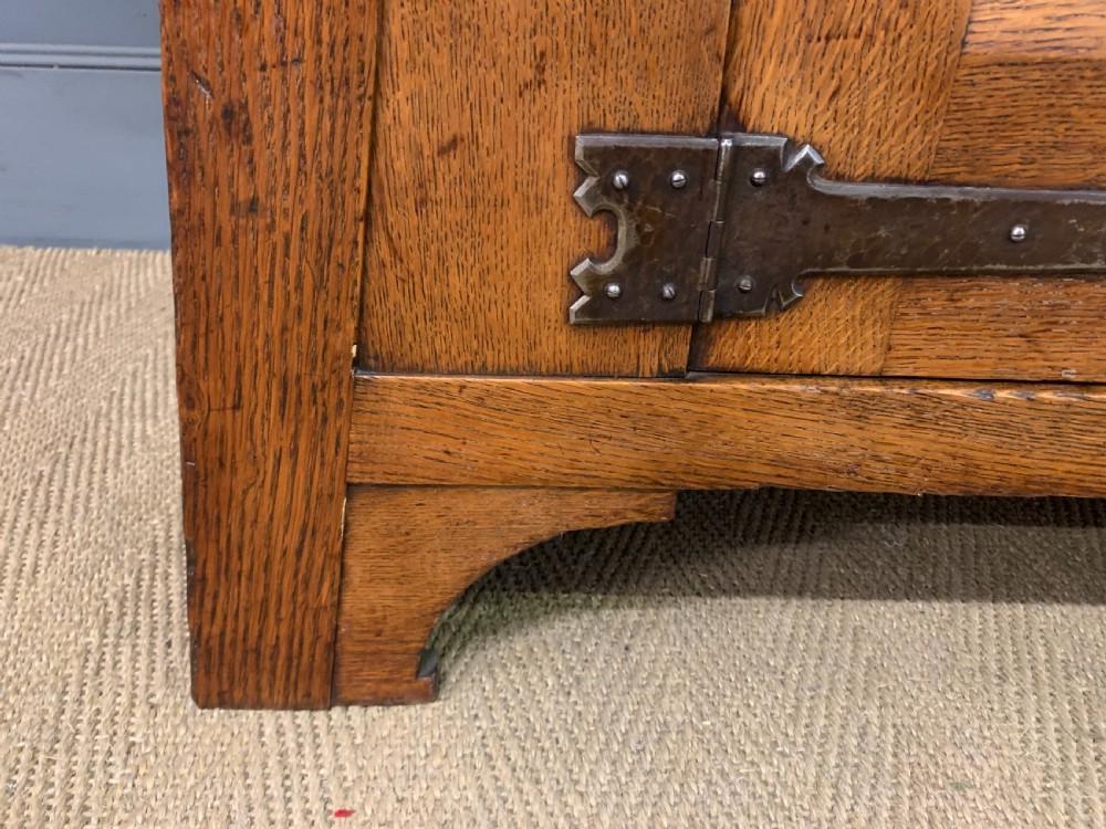 An Arts and Crafts period oak dresser featuring leaded glass upper cabinet doors, open side shelves, metal strap hinges, and a lower two-door cupboard. View XIII