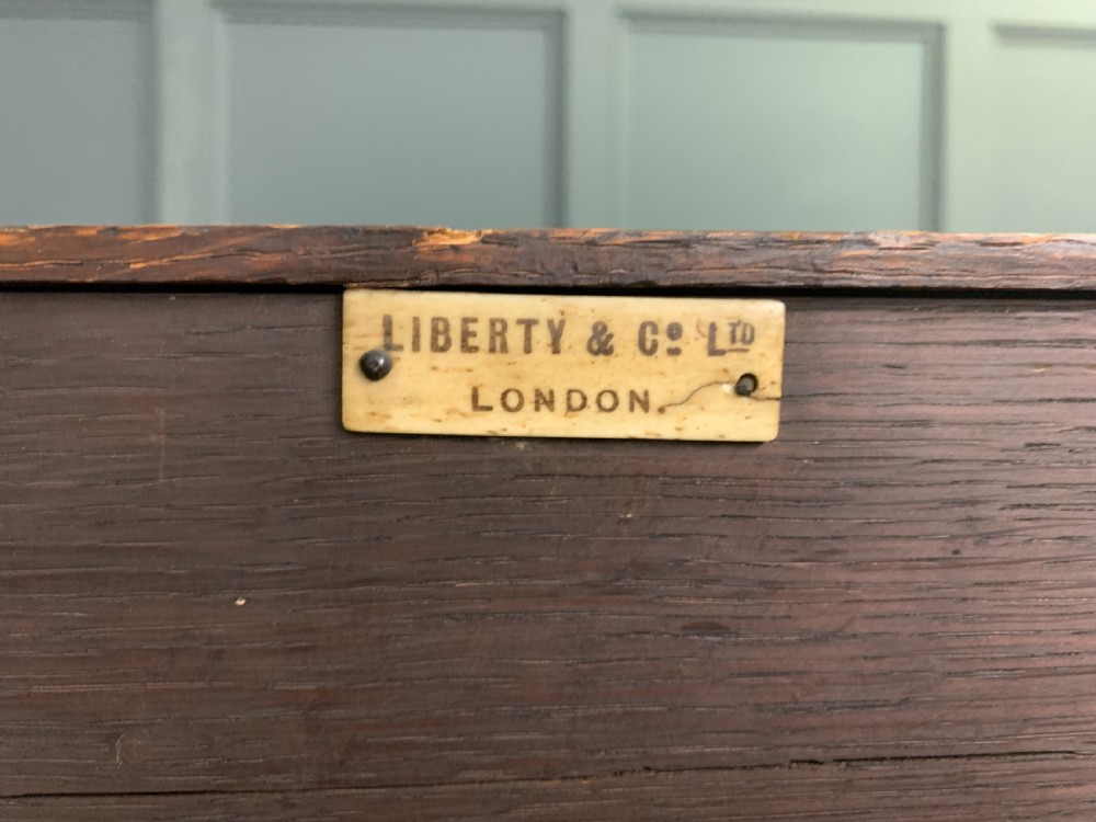 An Arts and Crafts period oak dresser featuring leaded glass upper cabinet doors, open side shelves, metal strap hinges, and a lower two-door cupboard. View XXV