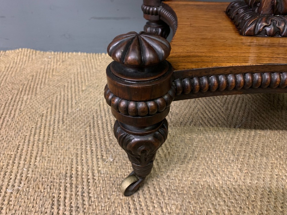 A Regency period rosewood fold-over card table with a swivel top, a central pedestal support, and a concave platform base resting on carved feet with brass castors. View V
