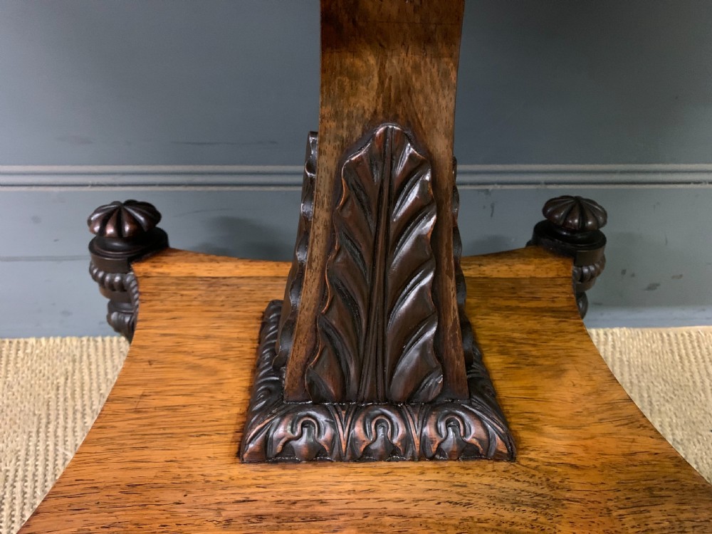 A Regency period rosewood fold-over card table with a swivel top, a central pedestal support, and a concave platform base resting on carved feet with brass castors. View VI