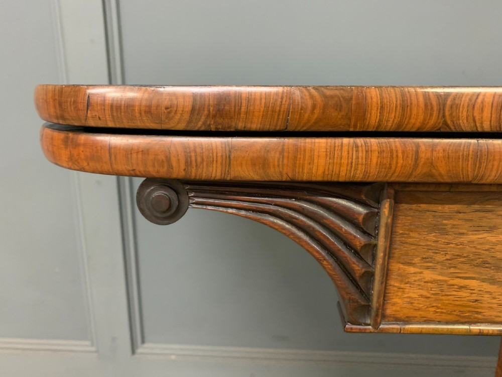 A Regency period rosewood fold-over card table with a swivel top, a central pedestal support, and a concave platform base resting on carved feet with brass castors. View VIII