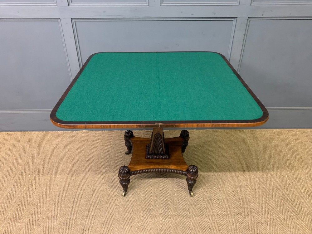 A Regency period rosewood fold-over card table with a swivel top, a central pedestal support, and a concave platform base resting on carved feet with brass castors. View XI