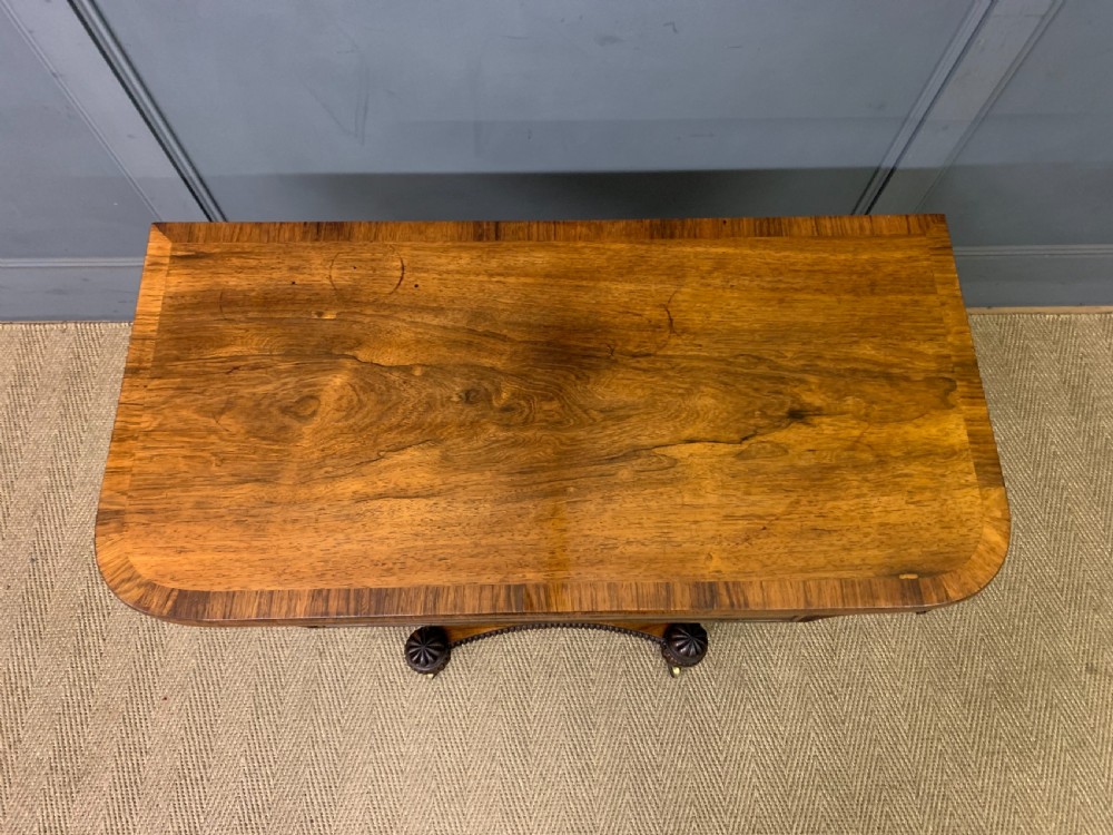 A Regency period rosewood fold-over card table with a swivel top, a central pedestal support, and a concave platform base resting on carved feet with brass castors. View XIII