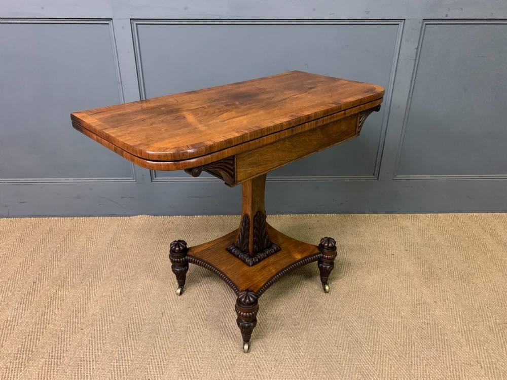 A Regency period rosewood fold-over card table with a swivel top, a central pedestal support, and a concave platform base resting on carved feet with brass castors. View XIV