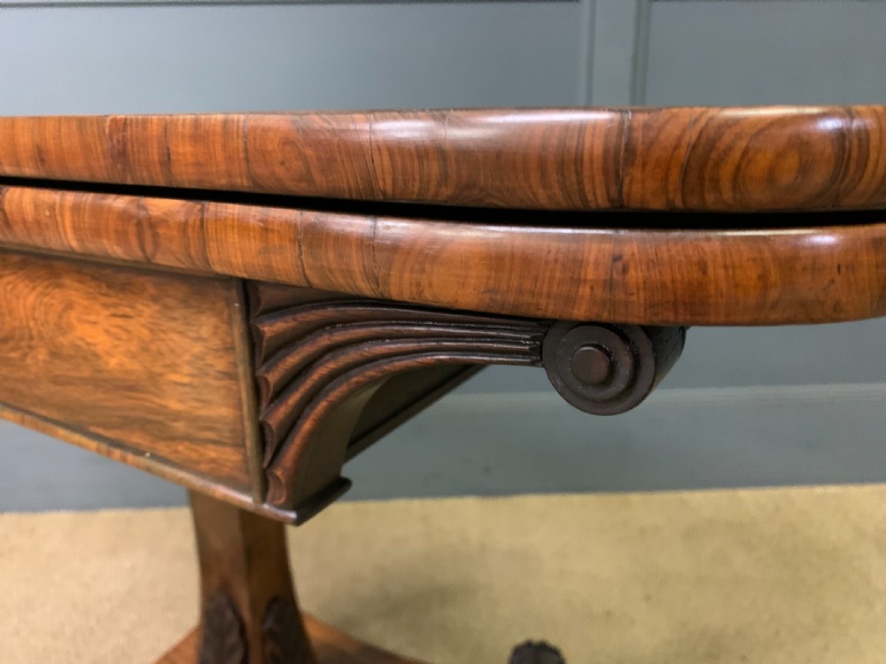 A Regency period rosewood fold-over card table with a swivel top, a central pedestal support, and a concave platform base resting on carved feet with brass castors. View XVIII