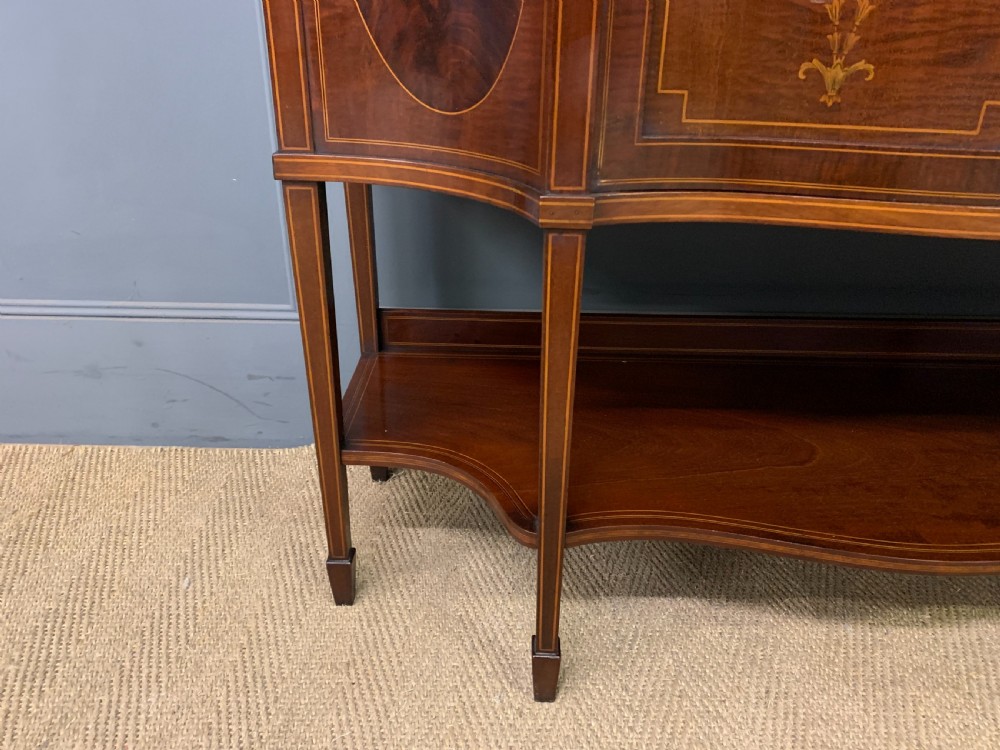 An Edwardian inlaid mahogany display cabinet featuring a glazed upper section, bow-front lower doors with marquetry panels, and tapered legs with a lower shelf. View IX