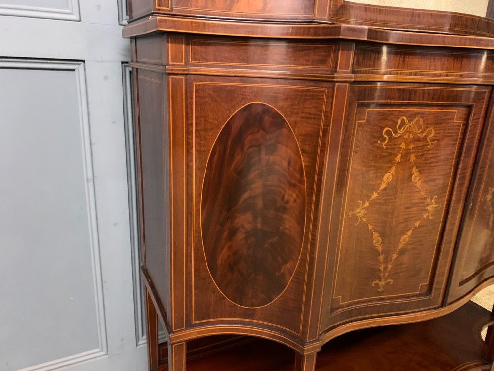 An Edwardian inlaid mahogany display cabinet featuring a glazed upper section, bow-front lower doors with marquetry panels, and tapered legs with a lower shelf. View XII
