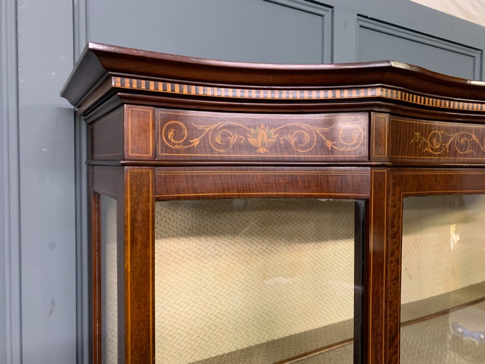 An Edwardian inlaid mahogany display cabinet featuring a glazed upper section, bow-front lower doors with marquetry panels, and tapered legs with a lower shelf. View XIII