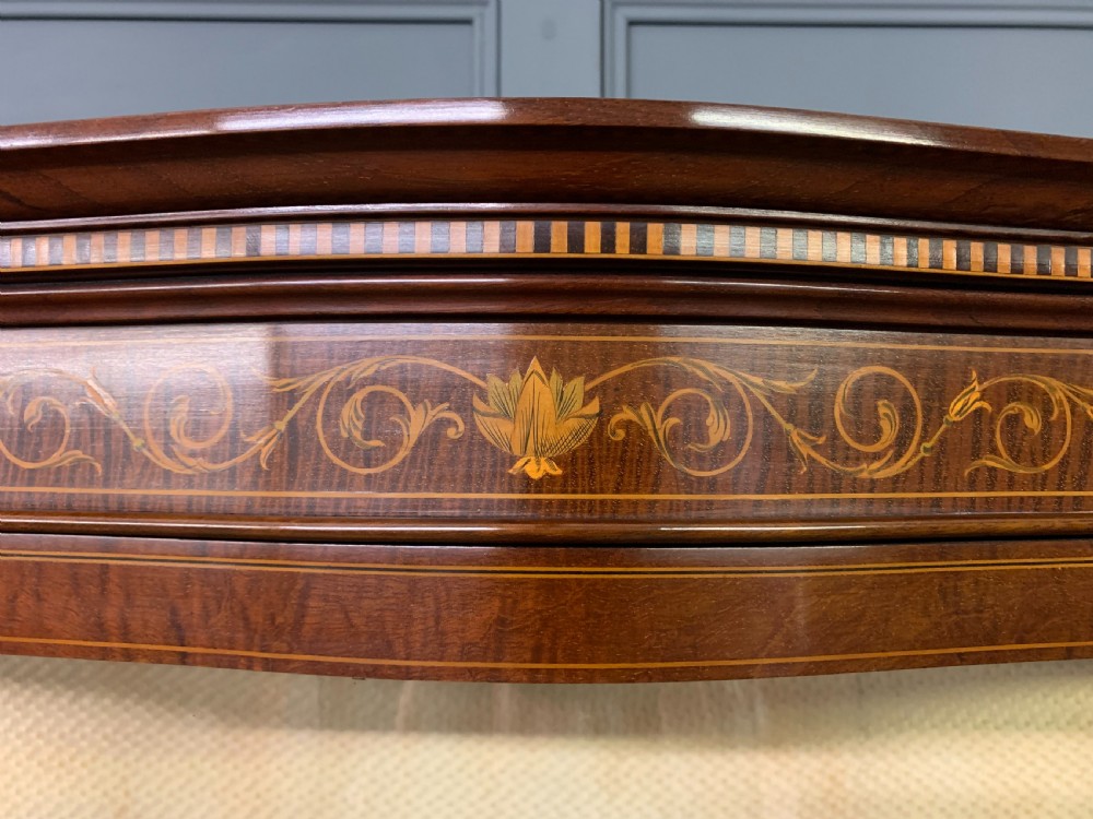 An Edwardian inlaid mahogany display cabinet featuring a glazed upper section, bow-front lower doors with marquetry panels, and tapered legs with a lower shelf. View XVI