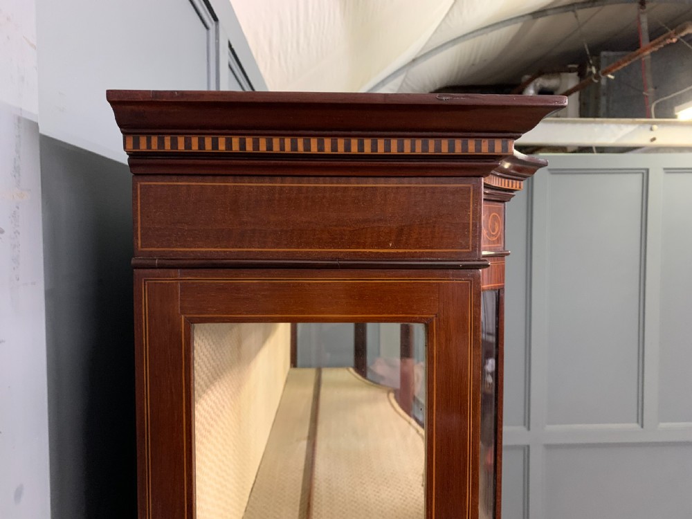 An Edwardian inlaid mahogany display cabinet featuring a glazed upper section, bow-front lower doors with marquetry panels, and tapered legs with a lower shelf. View XXIII