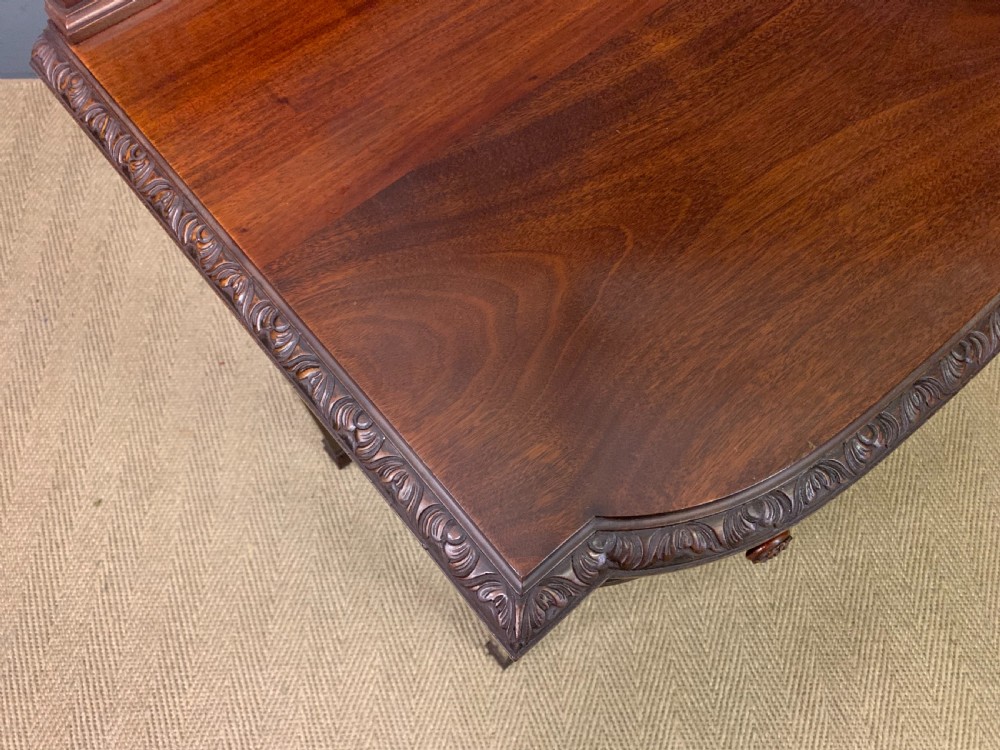 An Adam style mahogany side table featuring a carved upstand with an urn motif, relief drapery swags on the drawer fronts, and square fluted legs. View XIV