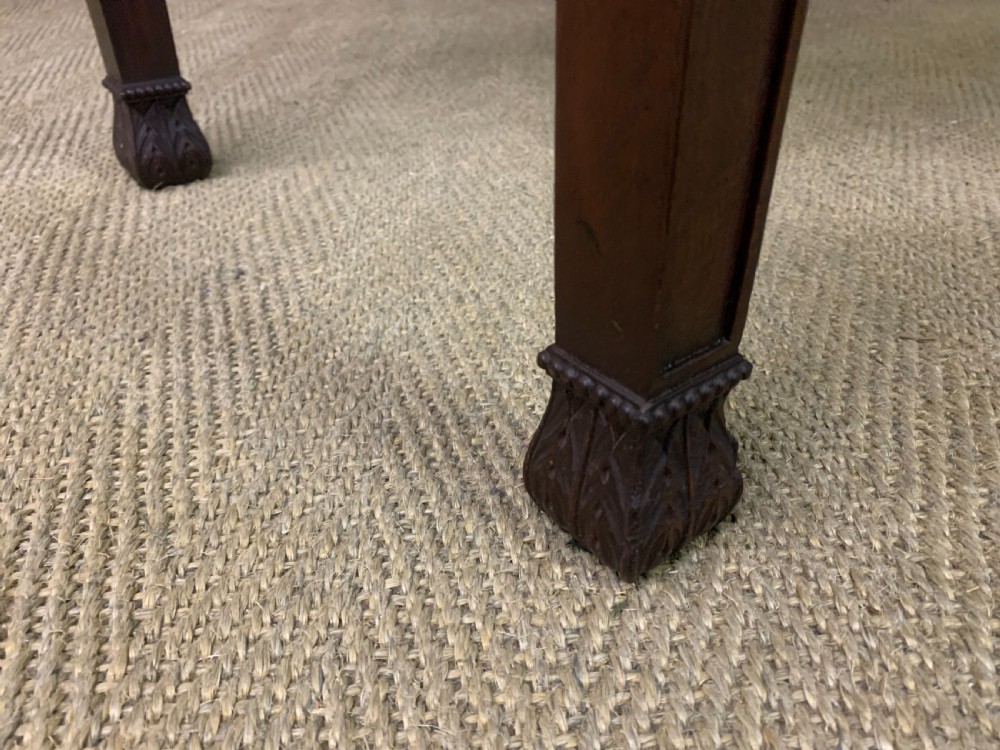 An Adam style mahogany side table featuring a carved upstand with an urn motif, relief drapery swags on the drawer fronts, and square fluted legs. View XVI