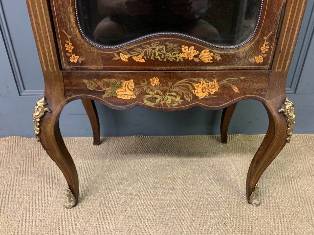 A freestanding mahogany vitrine featuring floral marquetry, a single glazed door, a brass top gallery, and cabriole legs with metal mounts. View IX
