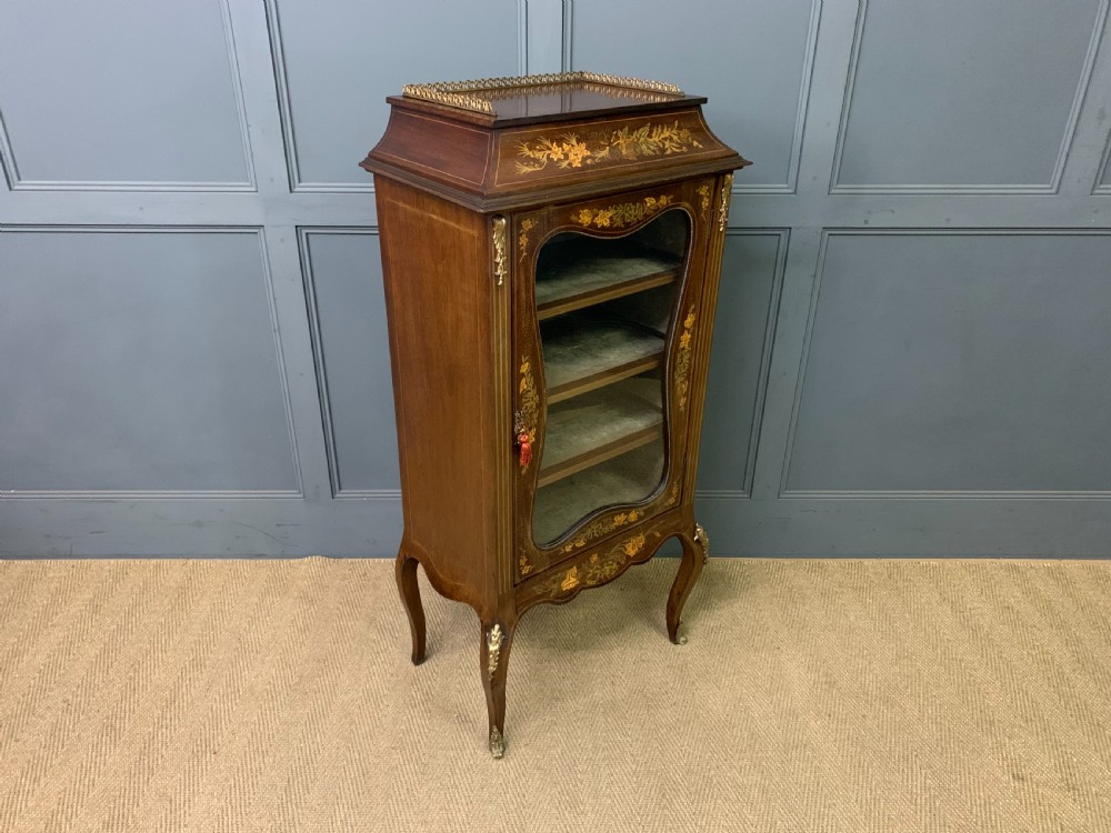 A freestanding mahogany vitrine featuring floral marquetry, a single glazed door, a brass top gallery, and cabriole legs with metal mounts. View XII