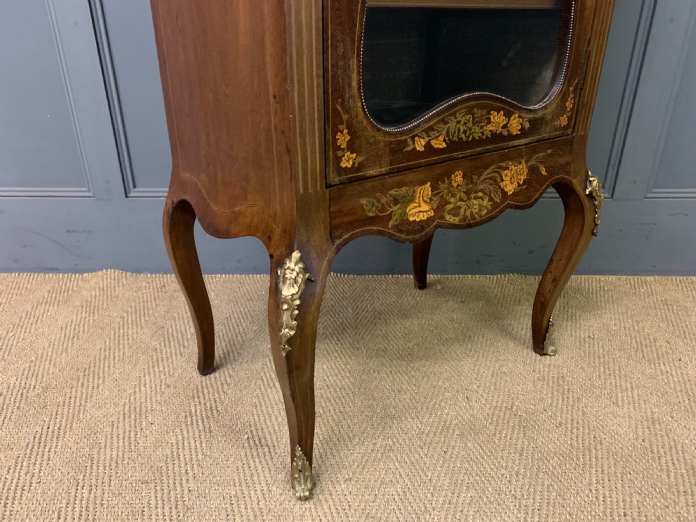 A freestanding mahogany vitrine featuring floral marquetry, a single glazed door, a brass top gallery, and cabriole legs with metal mounts. View XV