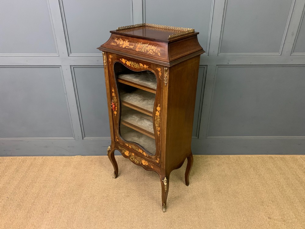 A freestanding mahogany vitrine featuring floral marquetry, a single glazed door, a brass top gallery, and cabriole legs with metal mounts. View XVII