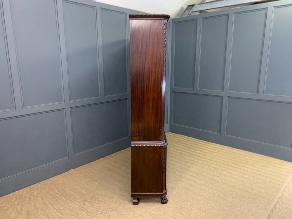 A tall mahogany Chippendale style glazed bookcase featuring three astragal glazed upper doors above three carved panelled lower cupboard doors resting on ball and claw feet. View III