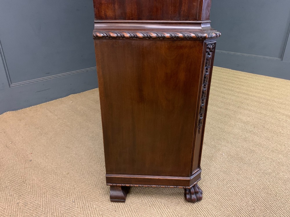 A tall mahogany Chippendale style glazed bookcase featuring three astragal glazed upper doors above three carved panelled lower cupboard doors resting on ball and claw feet. View V