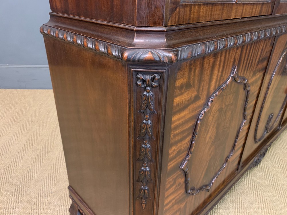 A tall mahogany Chippendale style glazed bookcase featuring three astragal glazed upper doors above three carved panelled lower cupboard doors resting on ball and claw feet. View VIII