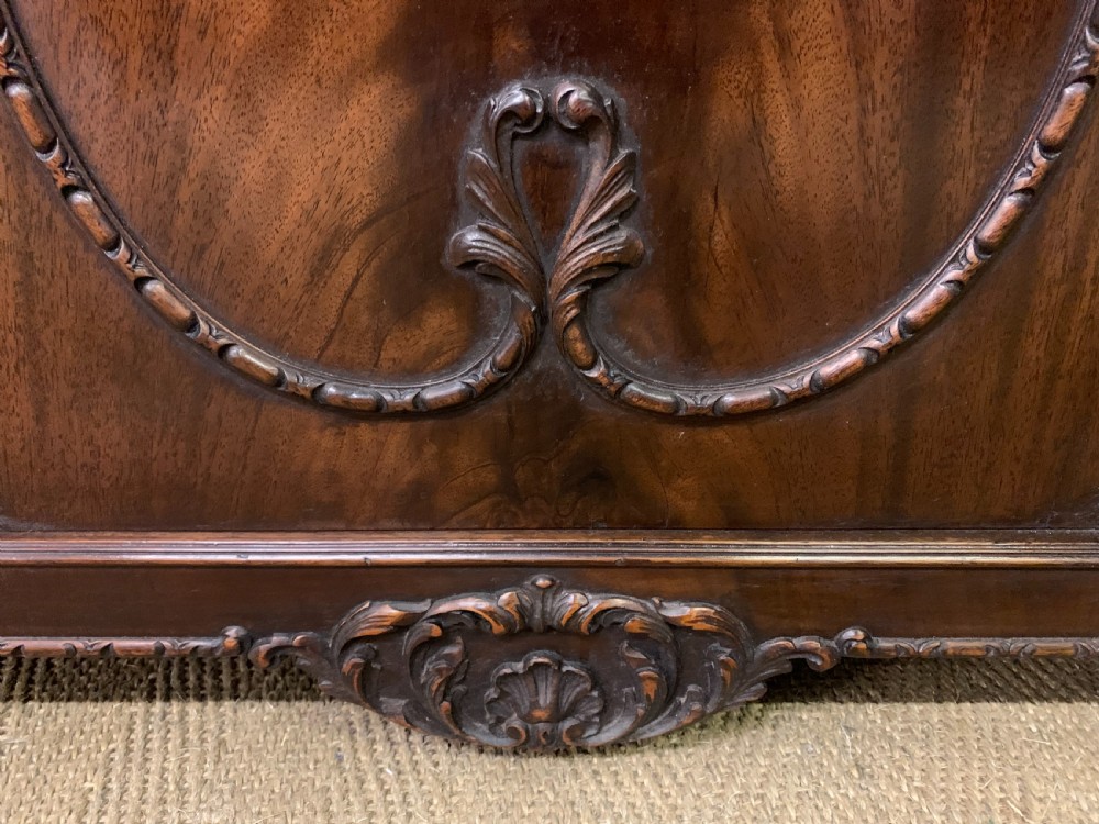 A tall mahogany Chippendale style glazed bookcase featuring three astragal glazed upper doors above three carved panelled lower cupboard doors resting on ball and claw feet. View XVI