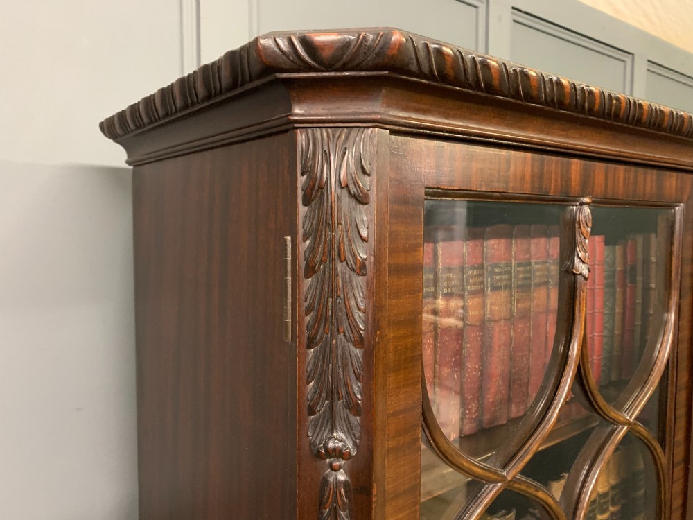 A tall mahogany Chippendale style glazed bookcase featuring three astragal glazed upper doors above three carved panelled lower cupboard doors resting on ball and claw feet. View XVII