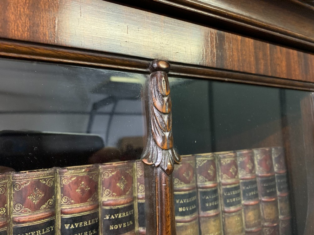 A tall mahogany Chippendale style glazed bookcase featuring three astragal glazed upper doors above three carved panelled lower cupboard doors resting on ball and claw feet. View XIX
