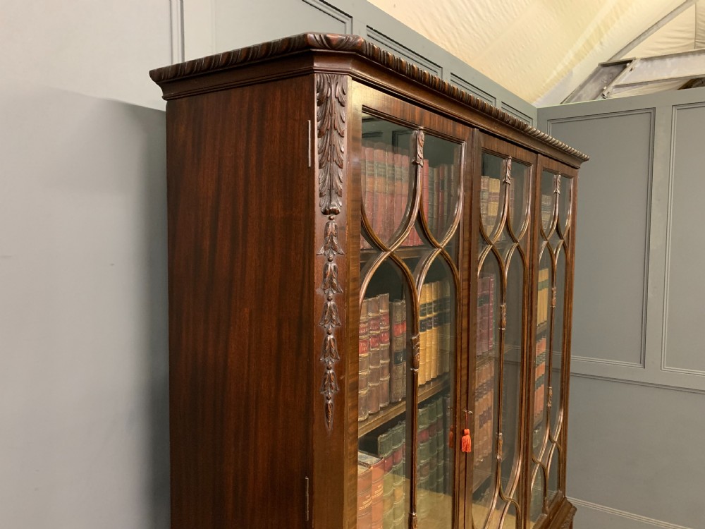 A tall mahogany Chippendale style glazed bookcase featuring three astragal glazed upper doors above three carved panelled lower cupboard doors resting on ball and claw feet. View XXI