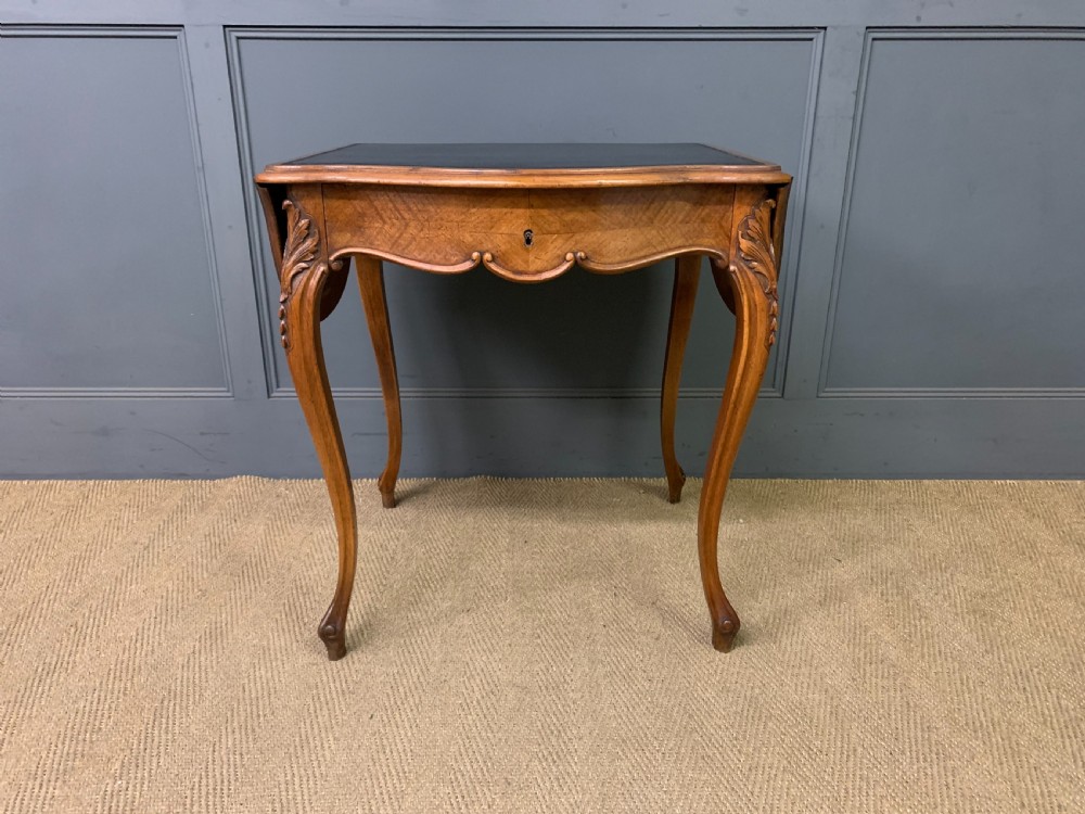 A French walnut drop-leaf table featuring cabriole legs with carved knee foliage and a black inset leather top surface. View III