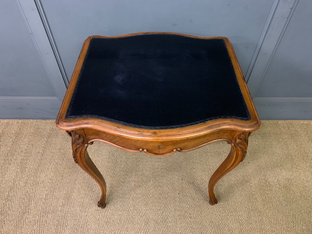 A French walnut drop-leaf table featuring cabriole legs with carved knee foliage and a black inset leather top surface. View IV