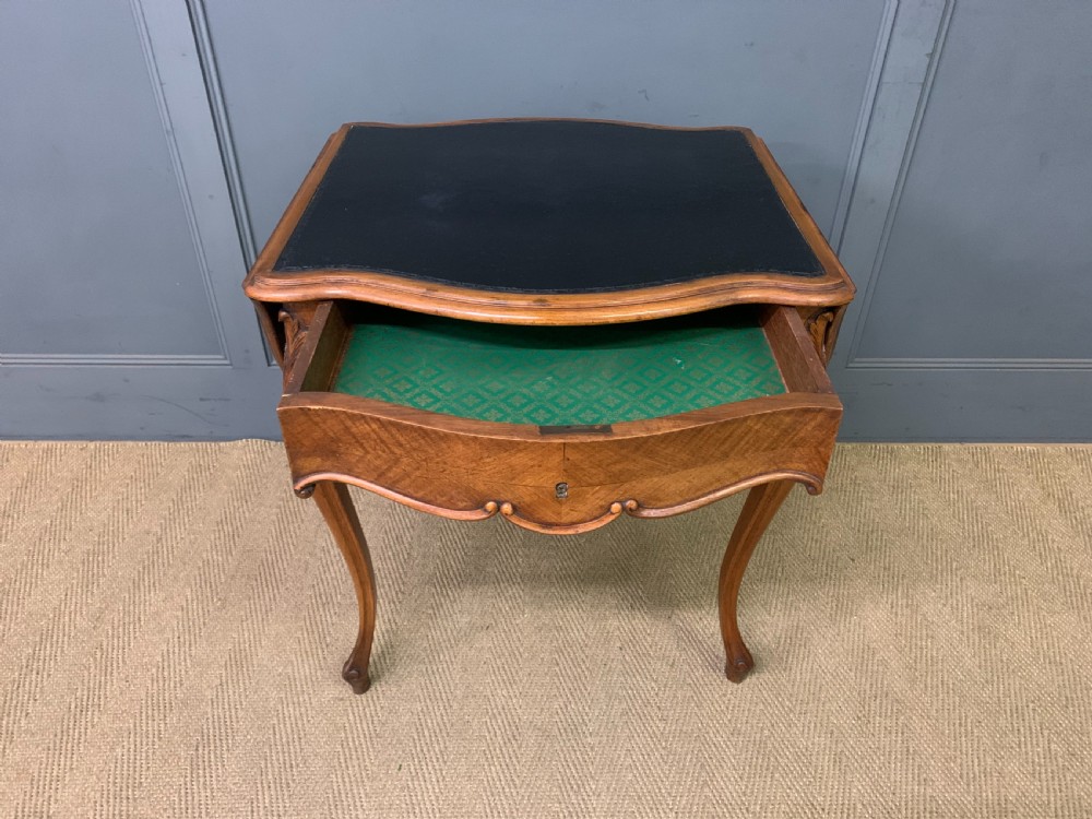 A French walnut drop-leaf table featuring cabriole legs with carved knee foliage and a black inset leather top surface. View V