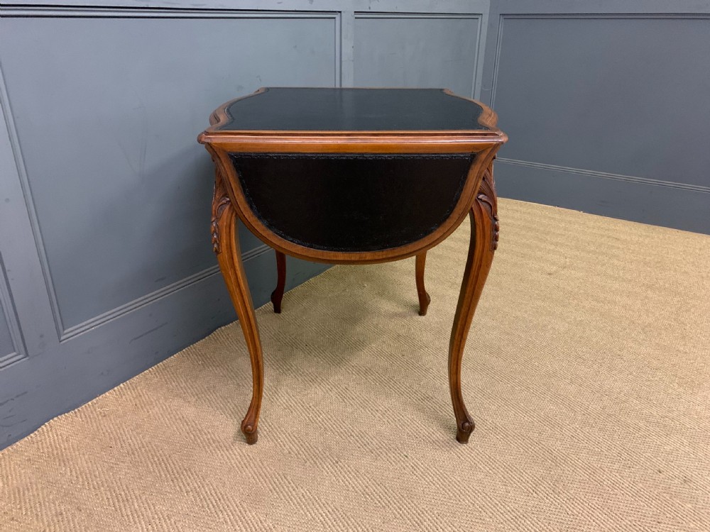 A French walnut drop-leaf table featuring cabriole legs with carved knee foliage and a black inset leather top surface. View VI