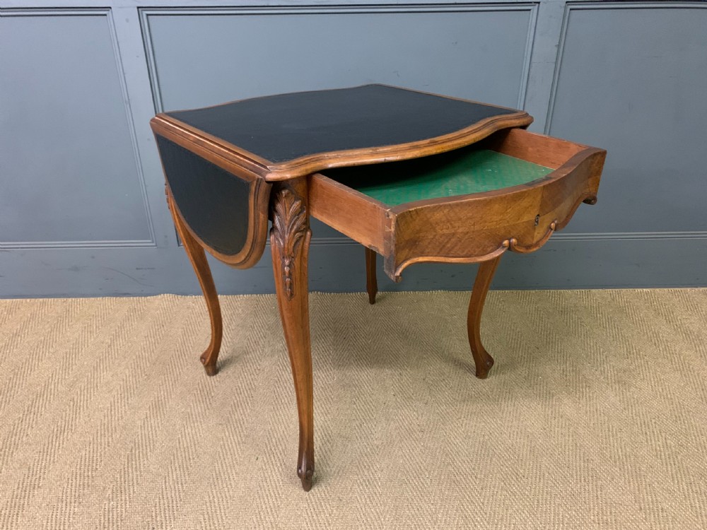 A French walnut drop-leaf table featuring cabriole legs with carved knee foliage and a black inset leather top surface. View VIII