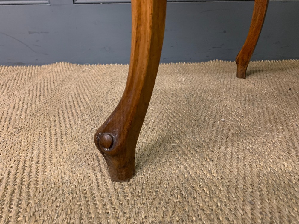 A French walnut drop-leaf table featuring cabriole legs with carved knee foliage and a black inset leather top surface. View XVI
