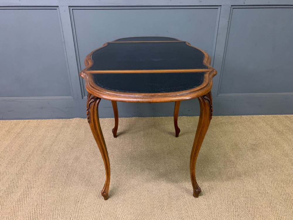A French walnut drop-leaf table featuring cabriole legs with carved knee foliage and a black inset leather top surface. View XVII