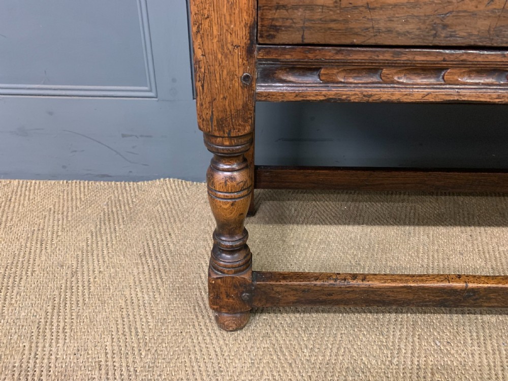 A carved oak Welsh dresser featuring an upper open shelving rack above two carved drawers and panelled cupboard doors resting on turned legs. View IV