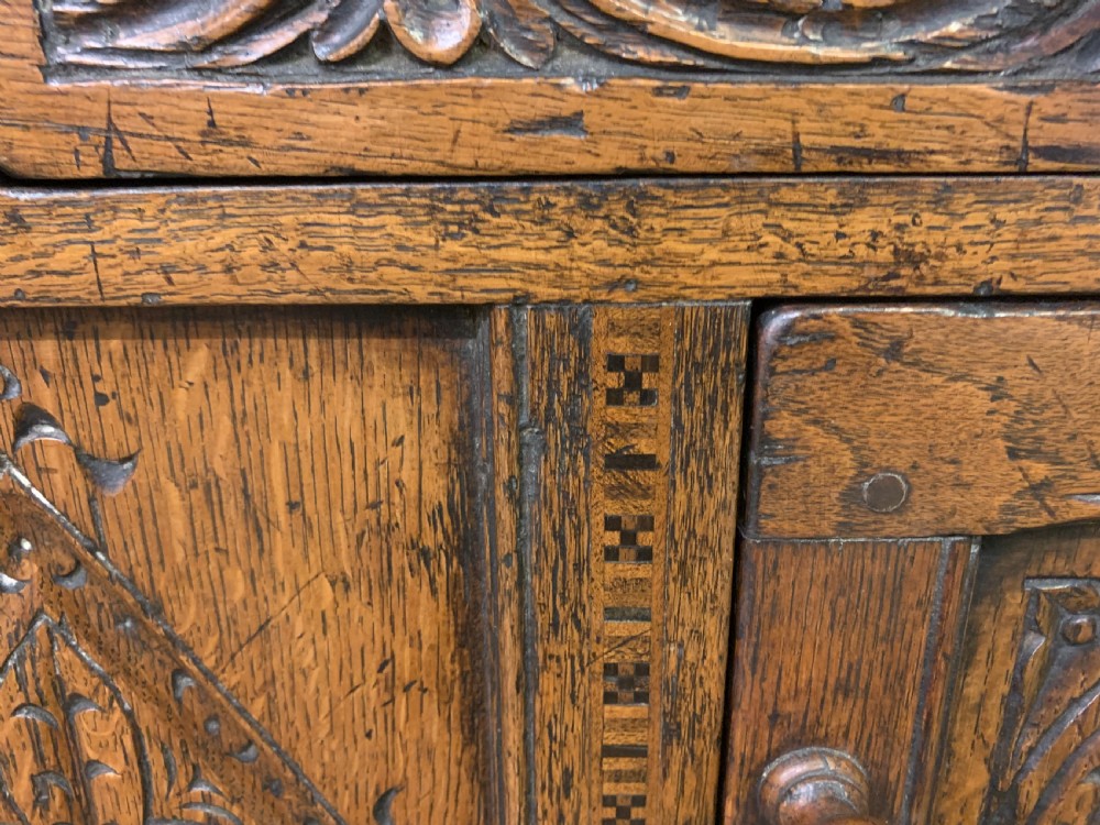 A carved oak Welsh dresser featuring an upper open shelving rack above two carved drawers and panelled cupboard doors resting on turned legs. View VII