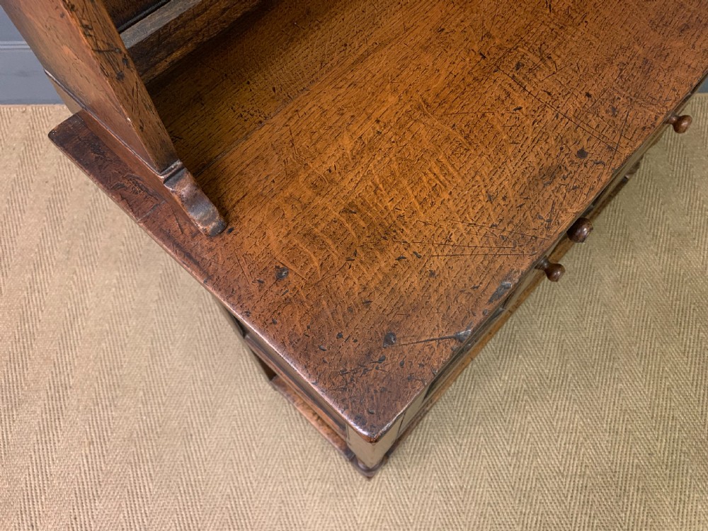 A carved oak Welsh dresser featuring an upper open shelving rack above two carved drawers and panelled cupboard doors resting on turned legs. View XV