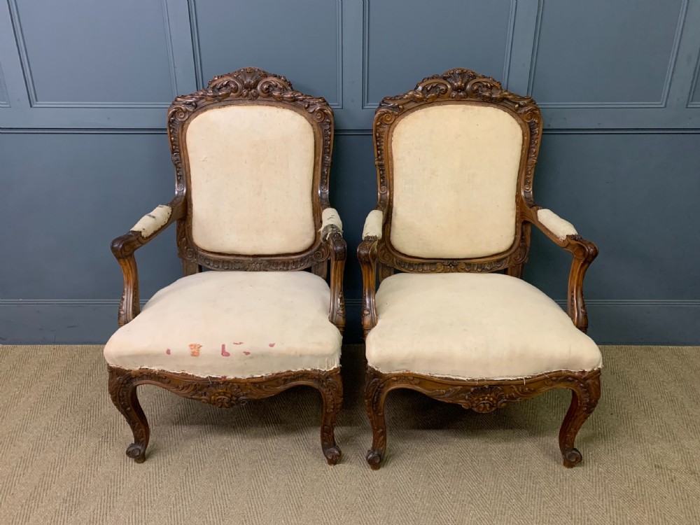 A pair of antique carved walnut French fauteuil armchairs featuring cream fabric upholstery and cabriole legs. View II