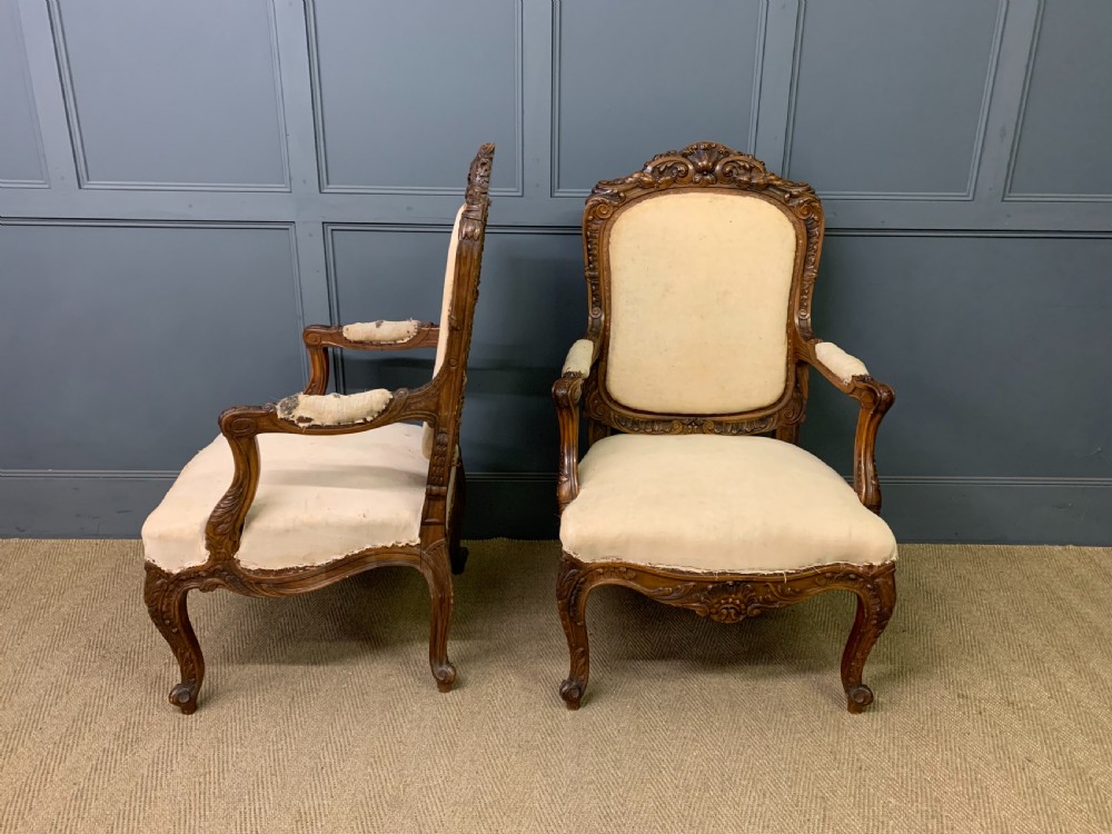 A pair of antique carved walnut French fauteuil armchairs featuring cream fabric upholstery and cabriole legs. View III