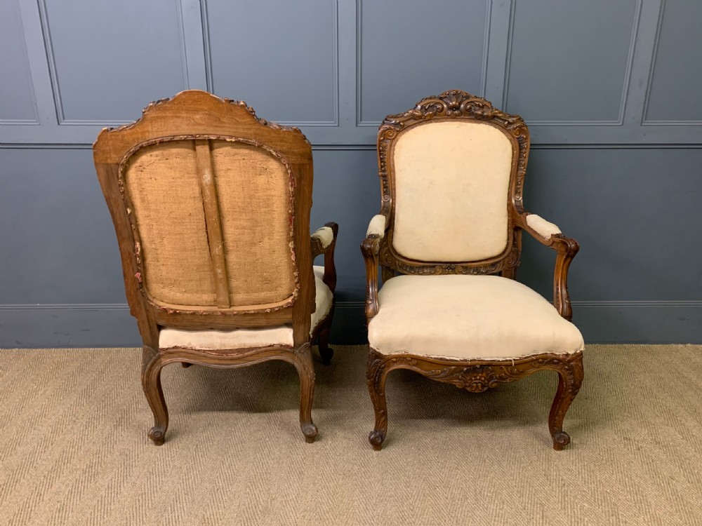A pair of antique carved walnut French fauteuil armchairs featuring cream fabric upholstery and cabriole legs. View IV