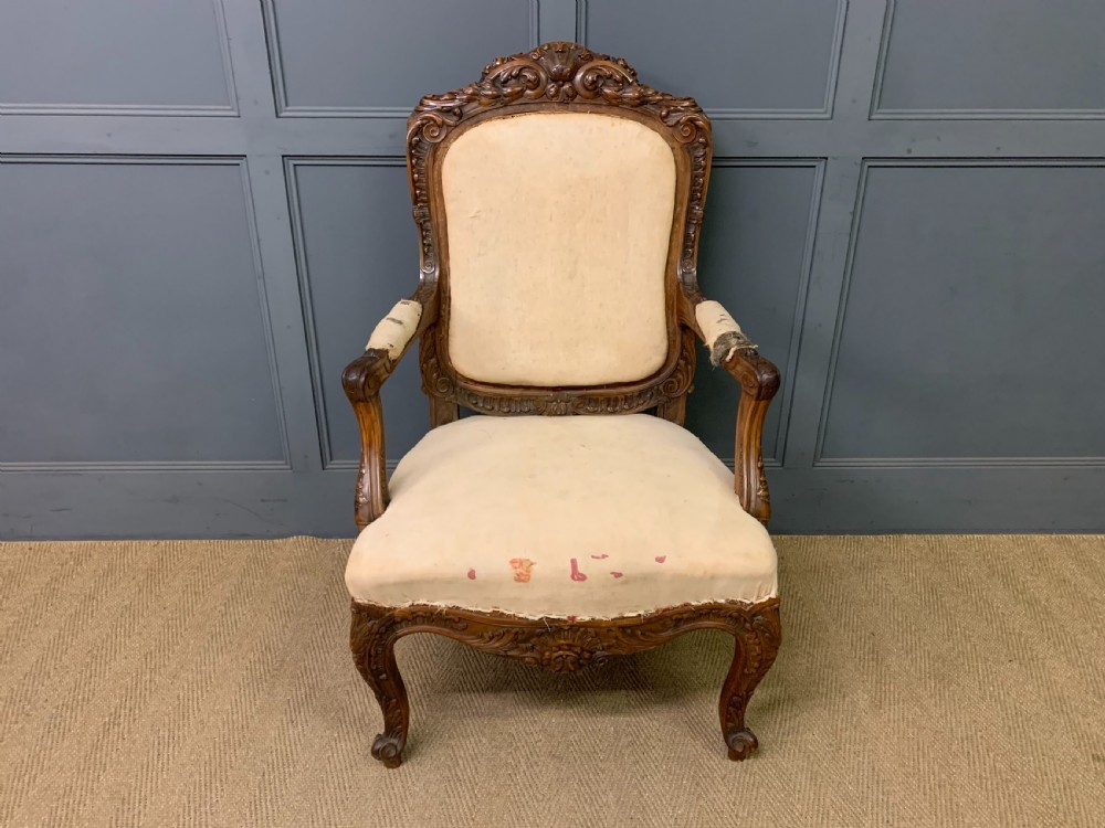 A pair of antique carved walnut French fauteuil armchairs featuring cream fabric upholstery and cabriole legs. View V