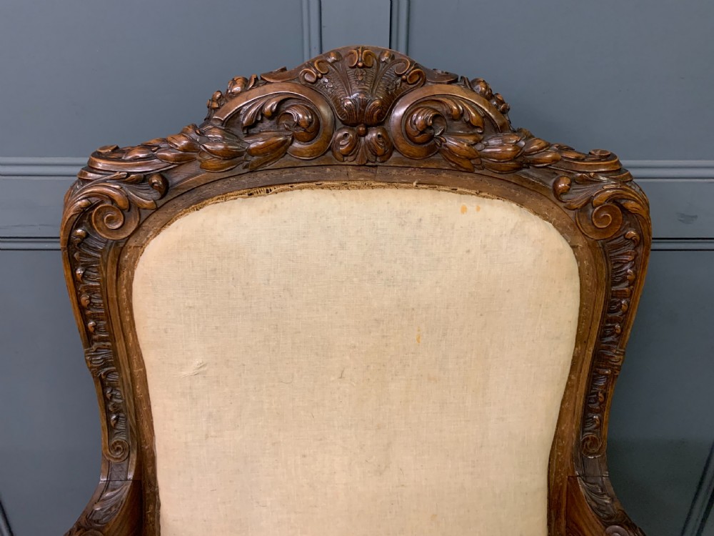 A pair of antique carved walnut French fauteuil armchairs featuring cream fabric upholstery and cabriole legs. View VI