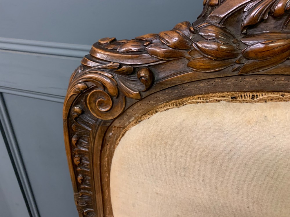 A pair of antique carved walnut French fauteuil armchairs featuring cream fabric upholstery and cabriole legs. View VIII