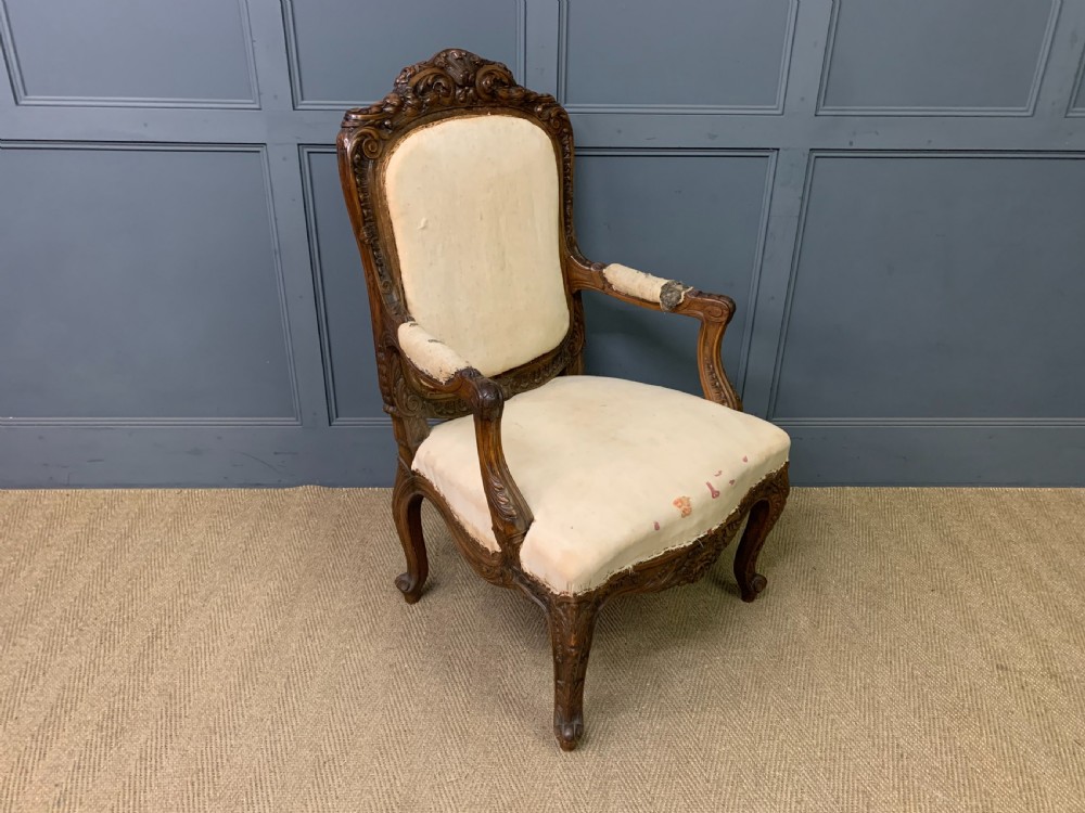 A pair of antique carved walnut French fauteuil armchairs featuring cream fabric upholstery and cabriole legs. View XI