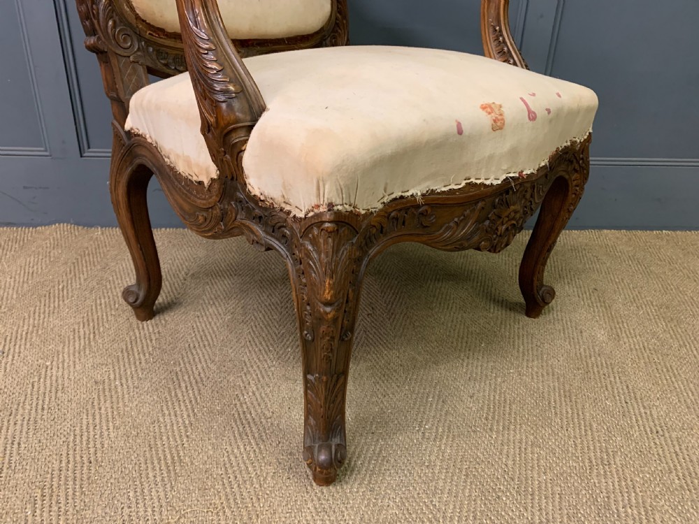 A pair of antique carved walnut French fauteuil armchairs featuring cream fabric upholstery and cabriole legs. View XII
