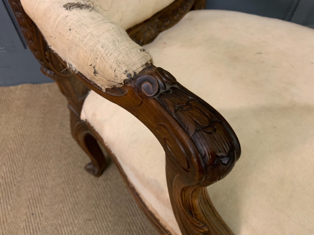 A pair of antique carved walnut French fauteuil armchairs featuring cream fabric upholstery and cabriole legs. View XIV
