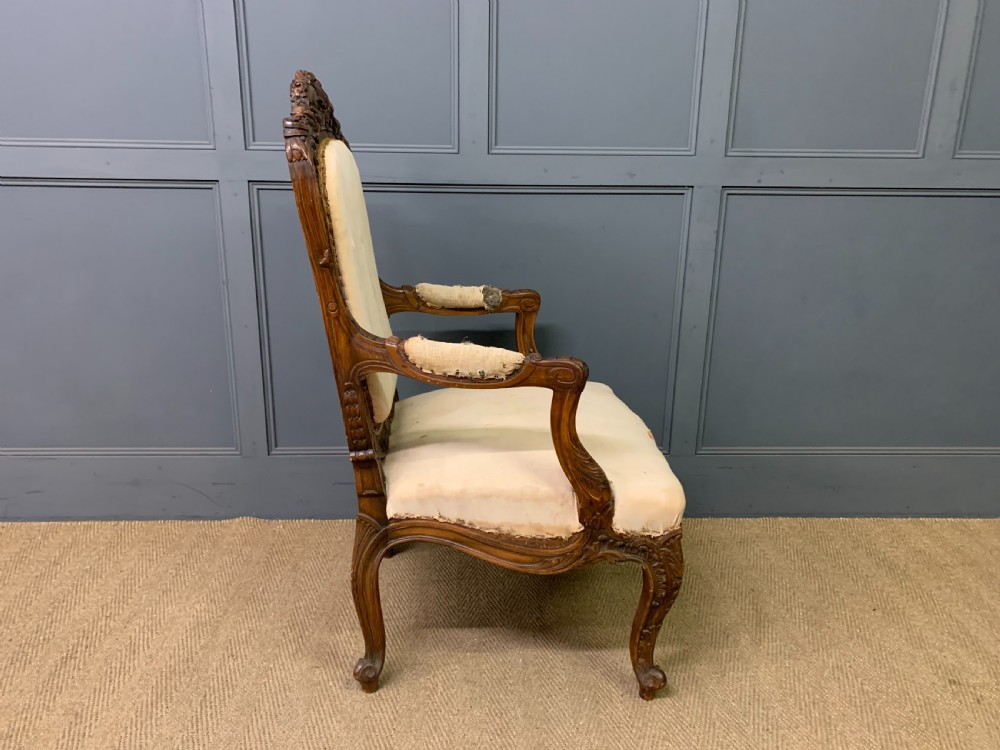 A pair of antique carved walnut French fauteuil armchairs featuring cream fabric upholstery and cabriole legs. View XVI