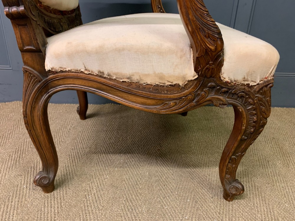 A pair of antique carved walnut French fauteuil armchairs featuring cream fabric upholstery and cabriole legs. View XVII