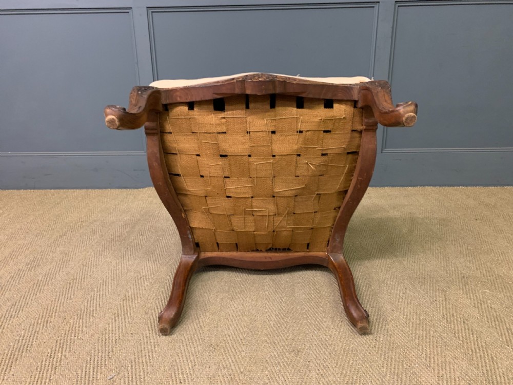 A pair of antique carved walnut French fauteuil armchairs featuring cream fabric upholstery and cabriole legs. View XVIII