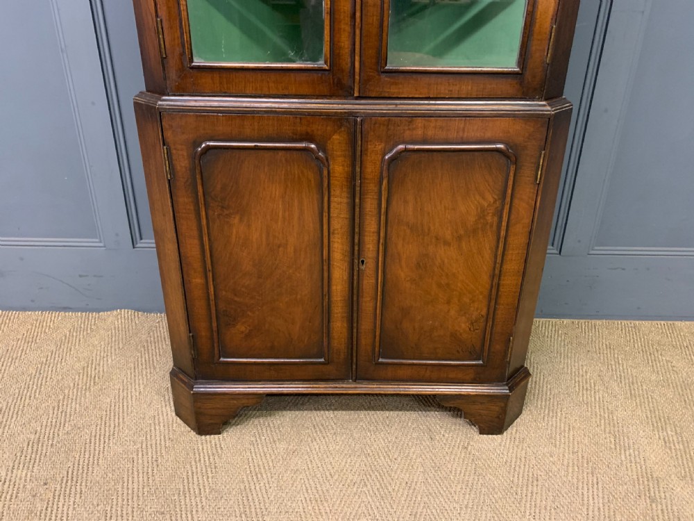 A tall burr walnut corner cabinet featuring an arched double-domed glazed upper section over a lower cupboard with panelled doors. View II